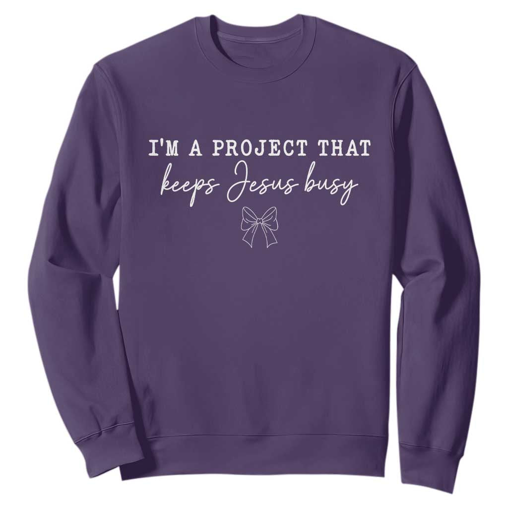 I am a Project That Keeps Jesus Busy Coquette Bow Sweatshirt Christian Faith Humor TS02 Purple Print Your Wear