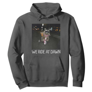 We Ride at Dawn Hoodie Funny Racoon Riding Tricycle Chaotic Meme TS14 Dark Heather Print Your Wear
